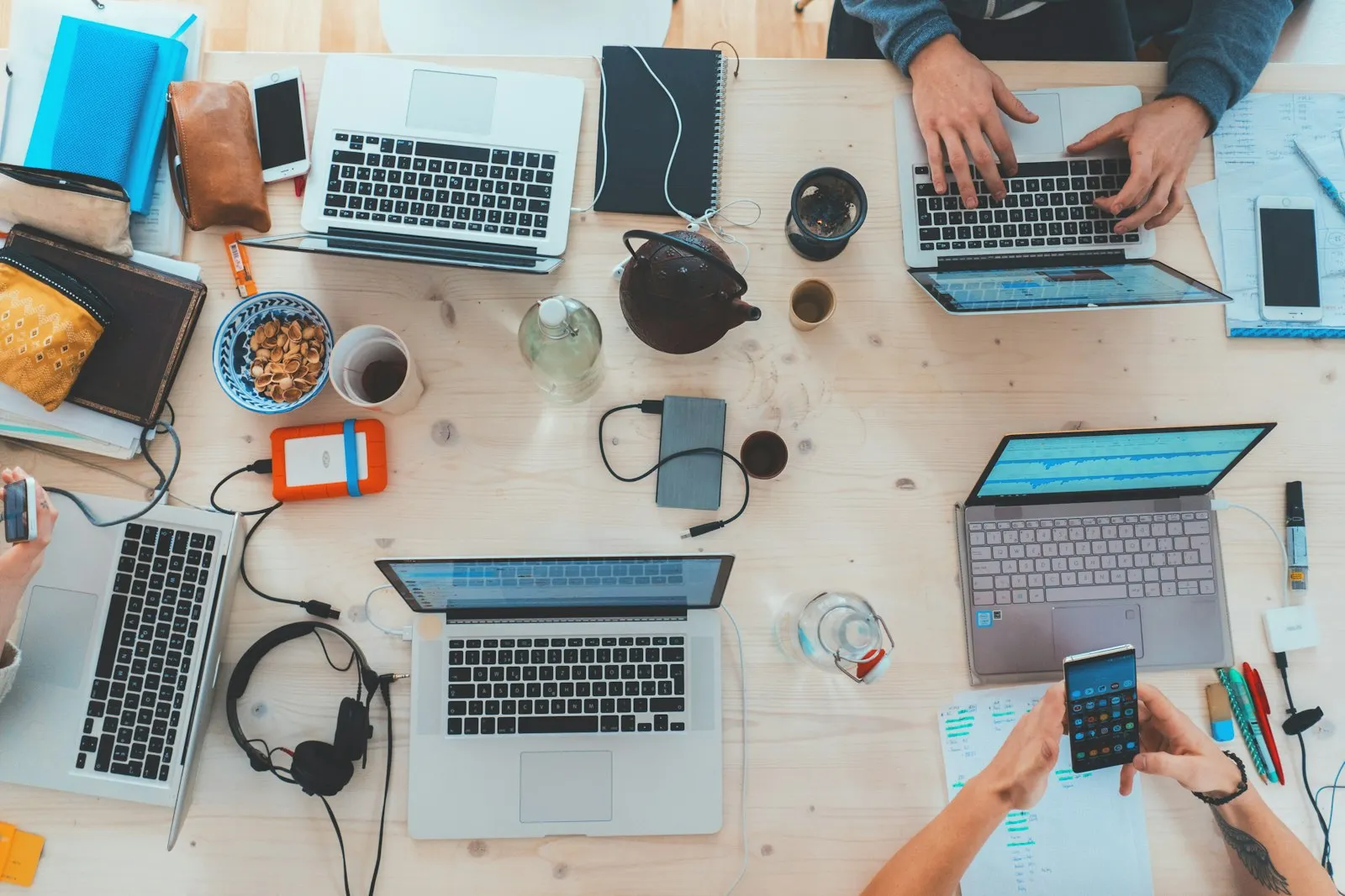 Tim developer bekerja bersama di sekitar meja dengan beberapa laptop